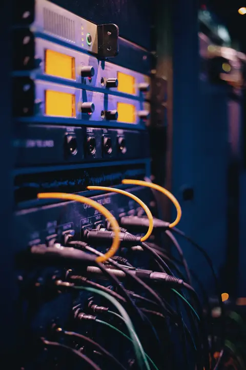 Close-up of a rack with orange and black patch cables landing on ports